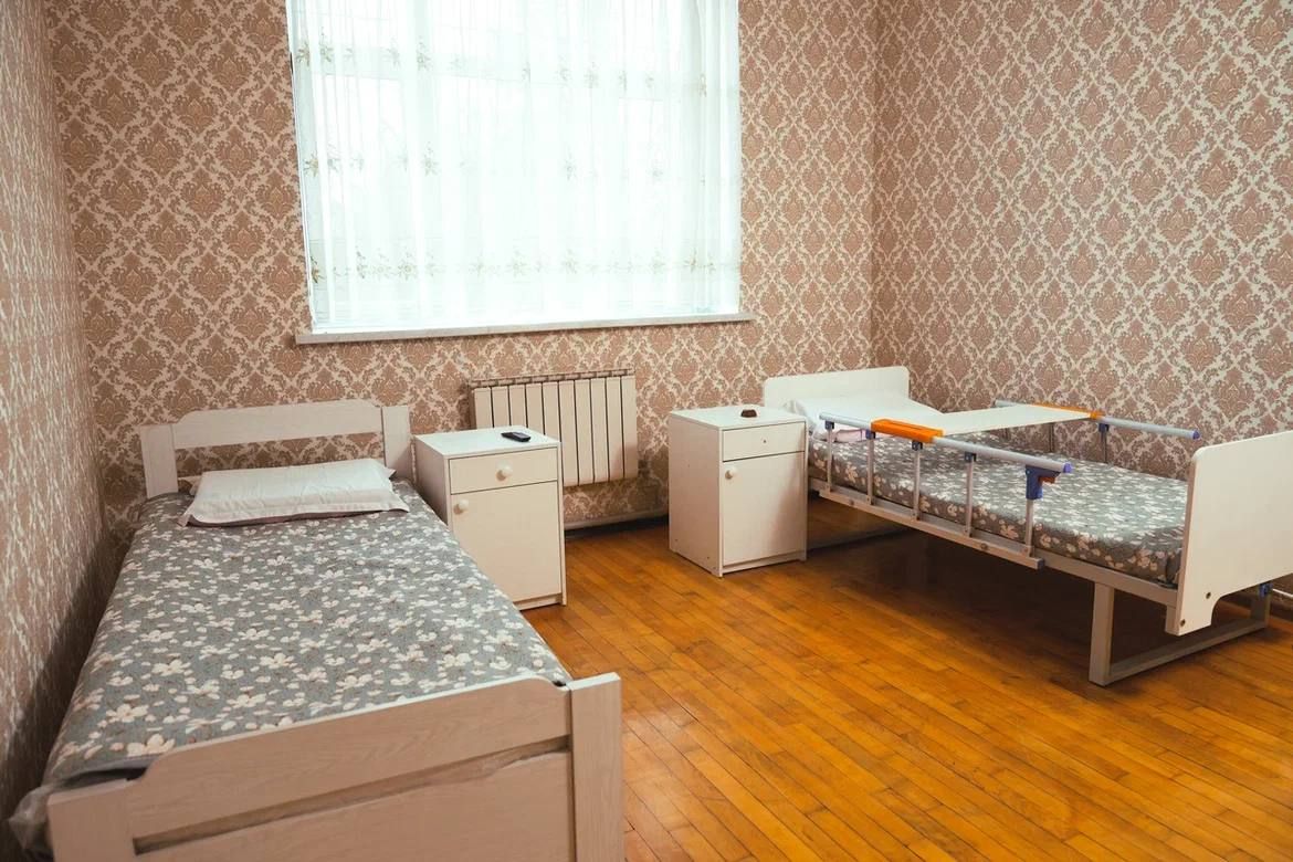 Двухместная палата: обычная кровать и функциональная медицинская с подъёмной спинкой, тумбочки у каждой
